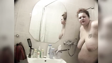 Толстая баба с трудом принимает душ в ванной комнате